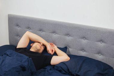 Geceleri yatak odasında, yatakta rahat uyuyan yakışıklı bir delikanlının en iyi görüntüsü. Farklı pozisyonlarda uyu. Bekar odası. Derin uyku.