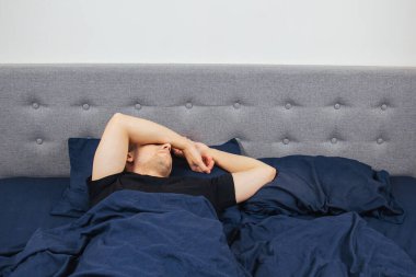 Geceleri yatak odasında, yatakta rahat uyuyan yakışıklı bir delikanlının en iyi görüntüsü. Farklı pozisyonlarda uyu. Bekar odası. Derin uyku.