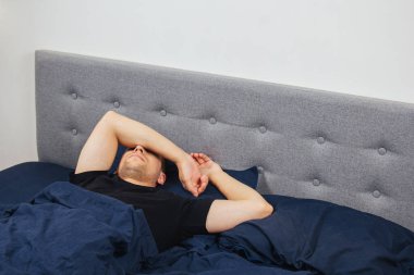 Geceleri yatak odasında, yatakta rahat uyuyan yakışıklı bir delikanlının en iyi görüntüsü. Farklı pozisyonlarda uyu. Bekar odası. Derin uyku.