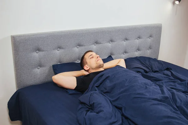 stock image Top view of a handsome young man sleeping comfortably on the bed at night in his bedroom. Sleep in different positions. Bachelor bedroom. Deep sleep