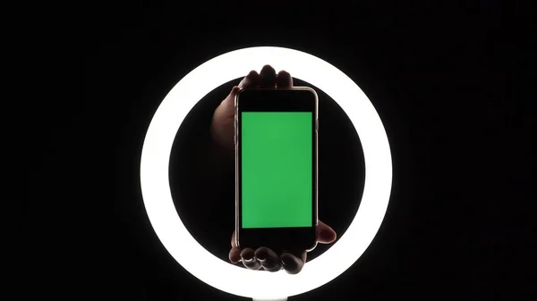 female hands show the phone close-up on a black background. green screen mockup for insert ads.