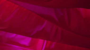 Light flowing red fabric imitating waves. The concept of lightness, female beauty, tenderness. Air show. Association with womens critical days