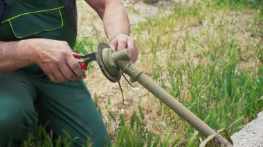 Close-up of a man's hand taking apart a lawn mower to replace parts. Maintains and repairs the weed cutter by replacing parts