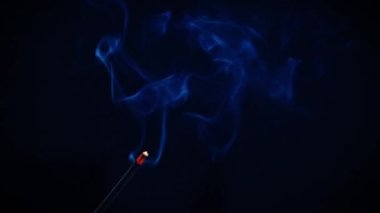 Incense sticks burn and smoke on a black background, incense smoke. Slow motion