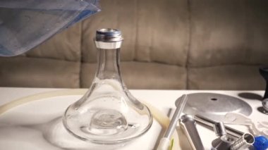 Cooking hookah. Step by step. A hookah man collects a hookah piece by piece in a hookah bar. Pours water into the flask