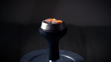 Close-up of burning embers on hookah. Square red coals ignite when hookah is inflated. Red coals burn on hookah cup. Process of preparing shisha