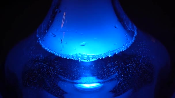煙の雲とテーブルの上にフカのガラス透明フラスコの閉じるまで 木製のテーブルの上に立って青いランプの光の下でShishaフラスコ — ストック動画
