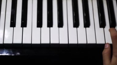 Piano keys close up in dark colors. Student trains to play the piano. Man two hands plays gentle classical music on a beautiful grand piano in a classroom close up