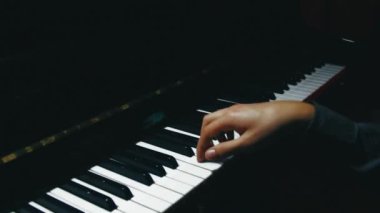 Piano keys close up in dark colors. Student trains to play the piano. Man two hands plays gentle classical music on a beautiful grand piano in a classroom close up