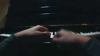 The student is learning to play the piano. A man with two hands plays a beautiful piano in the classroom close-up. Shot with a wide angle camera. Fish eye