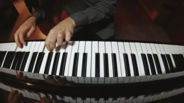 The student is learning to play the piano. A man with two hands plays a beautiful piano in the classroom close-up. Shot with a wide angle camera. Fish eye