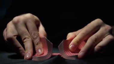 Casino: The hands of a male dealer shuffle poker cards. Tricks with cards