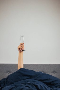 Yatakta bir adamın elinde şampanya. Akşamdan kalma, alkol zehirlenmesi konsepti. Tatil selamları.