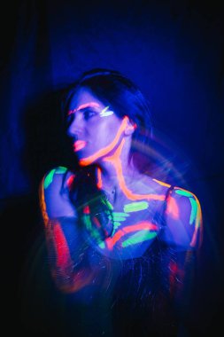 A beautiful young girl with makeup from ultraviolet paints smokes. Releases smoke from the mouth. Holiday of colors holly. Bright, colorful, festive coloring book. Fluorescent makeup on the face