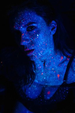 Portrait of a beautiful woman with blue sequins on her face. Girl with artistic make-up in Light color. Fashion model with colorful makeup