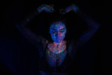 A beautiful young girl with makeup from ultraviolet paints smokes. Releases smoke from the mouth. Holiday of colors holly. Bright, colorful, festive coloring book. Fluorescent makeup on the face