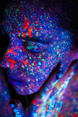 Portrait of a beautiful woman with blue sequins on her face. Girl with artistic make-up in Light color. Fashion model with colorful makeup