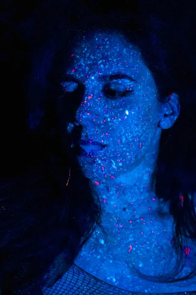 Portrait of a beautiful woman with blue sequins on her face. Girl with artistic make-up in Light color. Fashion model with colorful makeup