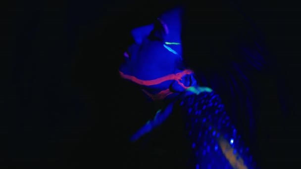 ネオンライトでモデル女性 蛍光メイクと美しいモデルの女の子 紫外線で踊るディスコダンサーのアートデザイン カラフルなメイク ナイトクラブ パーティー 4Kビデオ — ストック動画