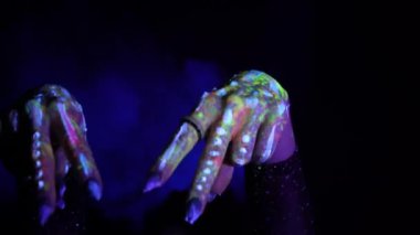 A hand with a fluorescent ethnic pattern shows two fingers. Fluorescent paint, body art concept. Glows in the dark. Gestures, symbols, hand movements