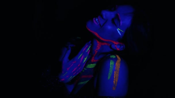 ネオンライトでモデル女性 蛍光メイクと美しいモデルの女の子 紫外線で踊るディスコダンサーのアートデザイン カラフルなメイク ナイトクラブ パーティー 4Kビデオ — ストック動画