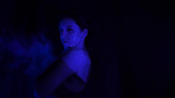 紫外線による化粧をした美少女が煙を描く 口から煙を出す 休日の色のホリー 明るく カラフルで お祝いの着色本 顔の蛍光メイク — ストック動画