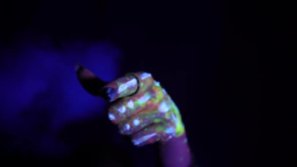 蛍光色の民族模様の手は 見る者に指を向けます 蛍光塗料 ボディアートの概念 暗闇の中で成長する ジェスチャー 手の動き — ストック動画