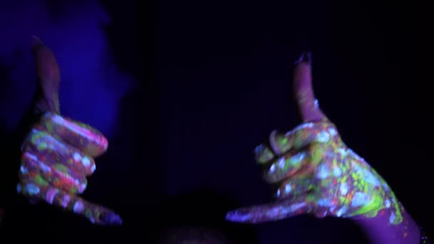蛍光色の民族模様の手は 電話や飲み物の申し出を示しています 蛍光塗料 ボディアートの概念 暗闇の中で成長する ジェスチャー 手の動き — ストック動画