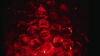 Water colored, red gel balls. Super macro bubbles slow motion. Background with hydrogel balls with glitter. The concept of cosmetology. Luminous, shiny capsules of vitamins for the face under a