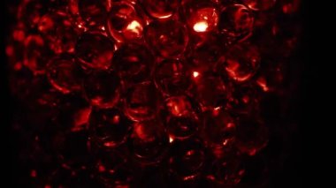 Water colored, red gel balls. Super macro bubbles slow motion. Background with hydrogel balls with glitter. The concept of cosmetology. Luminous, shiny capsules of vitamins for the face under a