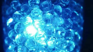 Water colored, blue gel balls. Super macro bubbles slow motion. Background with hydrogel balls with glitter. The concept of cosmetology. Luminous, shiny capsules