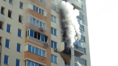 Kyiv, Ukraine - November 15, 2022: Firefighter sprays water on the walls to extinguish the fire. Lots of smoke rising up. Fire and thick gray smoke from broken windows during a major fire