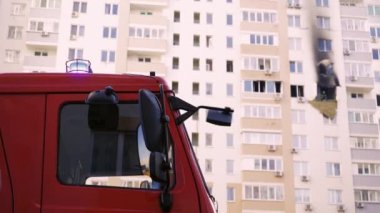 KYIV, UKRAINE - NOVEMBER 15, 2022: A red fire engine stands in front of a burned-out apartment in a multi-storey residential building. Fire after exploding generator