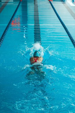 Beautiful female swimmer using front bypass, freestyle in the pool. Preparing professional athletes to win the championship