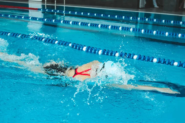 Female swimmer racing in the pool. A professional athlete overcomes stress and adversity in the pool