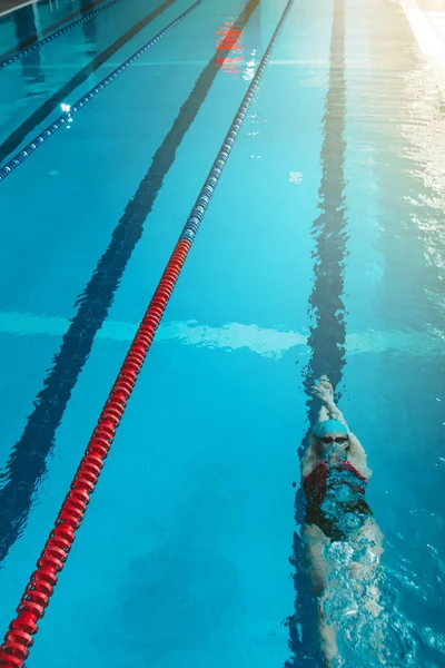 俯瞰一位年轻女子游泳运动员在游泳池里的训练 背着她在水里游泳 浮在水下吹气圈 — 图库照片