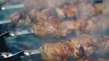 Yakın plan et şişleri. Şişte barbekü. Izgara ızgara. Boş zaman, yemek, insanlar, tatiller. Kavram - bir adam arkadaşları için barbekü ızgarasında et pişirir.