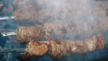 Yakın plan et şişleri. Şişte barbekü. Izgara ızgara. Boş zaman, yemek, insanlar, tatiller. Kavram - bir adam arkadaşları için barbekü ızgarasında et pişirir.