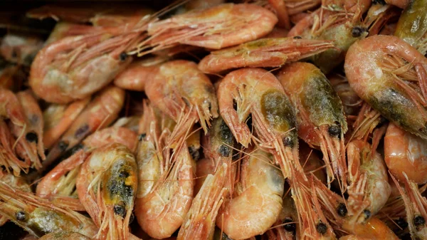 Pink fresh frozen shrimps with ice in a supermarket or fish shop. Uncooked seafood close up background. Fresh frozen prawns, delicacies, sea food concept, close up