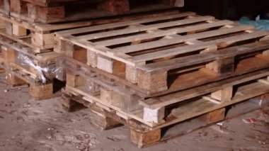 Palet rafı deposu, lojistik merkezi. Kocaman, büyük, modern bir depo. Boş ahşap paletler bir depoya istiflenmiş. Mağazada yığılmış bir sürü boş palet var.
