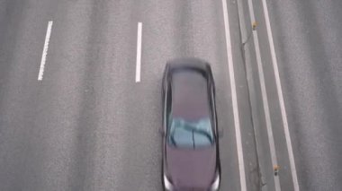 Yukarıdan 4K Manzara, pistten hızla geçen arabalara bakıyor. Kentsel yaşam ve taşımaya uzun süre maruz kalma