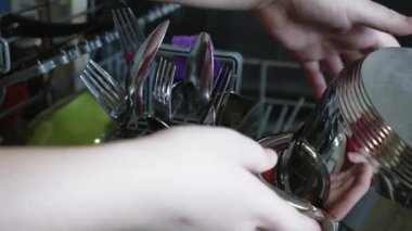 Kirli tabakları, çanak çömleği ve bardağı bulaşık makinesine yüklüyorlar. Kirli bulaşıkları bulaşık makinesine koyuyor. Mutfak aletleriyle günlük ev işleri. Bir ev hanımı mutfağı temiz tutmak için modern teknoloji kullanır.