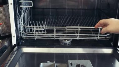 Kirli tabakları, çanak çömleği ve bardağı bulaşık makinesine yüklüyorlar. Kirli bulaşıkları bulaşık makinesine koyuyor. Mutfak aletleriyle günlük ev işleri. Bir ev hanımı mutfağı temiz tutmak için modern teknoloji kullanır.