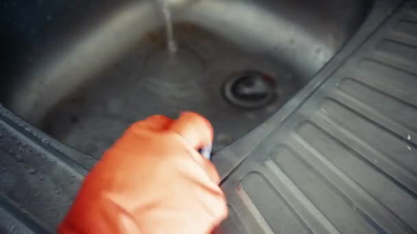 フォーム洗剤でステンレス製のキッチンシンクを掃除します 赤いゴム手袋の女性 汚れの洗浄 — ストック動画