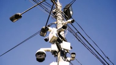 Birçok CCTV kamerası insanların güvenliğini sağlamak için kurulmuştur. Parlak bir gökyüzünün arka planına karşı. Modern teknoloji kavramı, yüz tanıma, mahremiyet yok