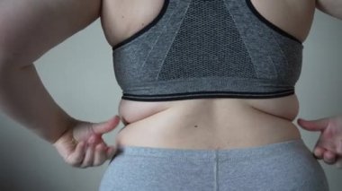 Şişman bir kadının göbeğinde yağ kıvrımlarının yakın çekimi. Aşırı kilolu, kadın obezite, diyet ve aşırı kilo sorunları kavramı