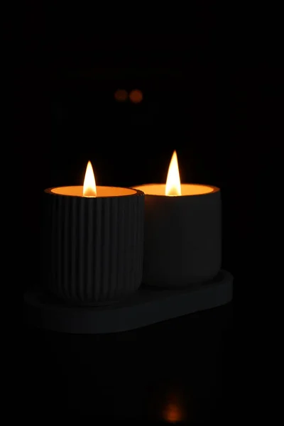 一组点燃的白色蜡烛在黑暗中闪烁着 在黑色的背景上 有一支蜡烛聚焦在前景中 点燃一支蜡烛 一个燃烧的蜡烛 漂亮的手工蜡烛房子里舒适的气氛 — 图库照片