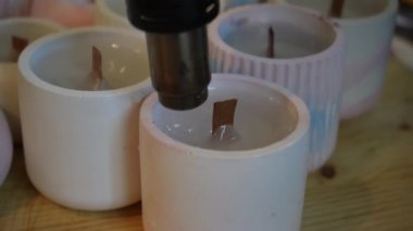 Bitmiş mumları yüzeyi düzleştirmek için saç kurutma makinesiyle işleme sokma işlemi. Mum üretimi için bir fabrika. El yapımı.