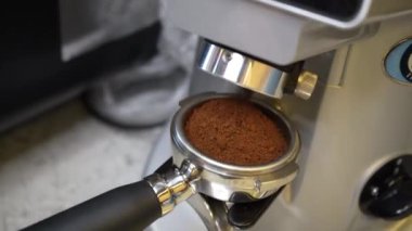Öğütücüden öğütücü kahve dökülüyor ve yavaşça iskele filtresine dökülüyor. Kahve çekirdeklerini öğütme süreci. Kapat.