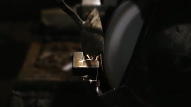 Erkek eli makinede çalışır. Sıcak metalden kıvılcımlar çıkıyor. Adam çelik üzerinde çok çalıştı. Elektrik öğütücüsünde bileme makinesi, döner taşta elle keskinleştirme, yakın plan.
